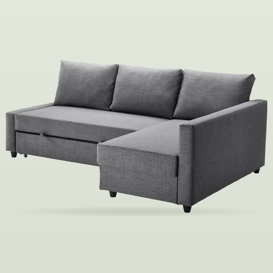 Dark grey corner sofa bed with a chaise longue on the right and three back cushions, on a pale sage background