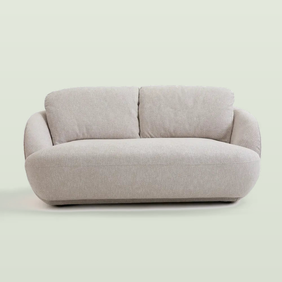 Low bench sofa in heathered greige cotton with two loose back cushions and rounded arms, front view on a pale sage background
