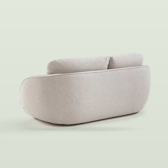 Back view of the bench sofa: the rounded back wraps around the loose back cushions, on a pale sage background