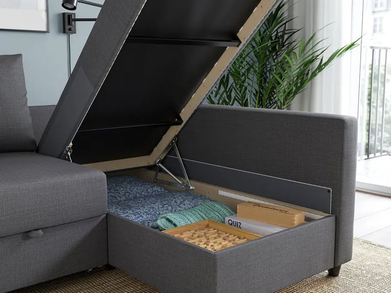The chaise longue of the grey corner sofa with its seat lifted, showing bedding stored inside
