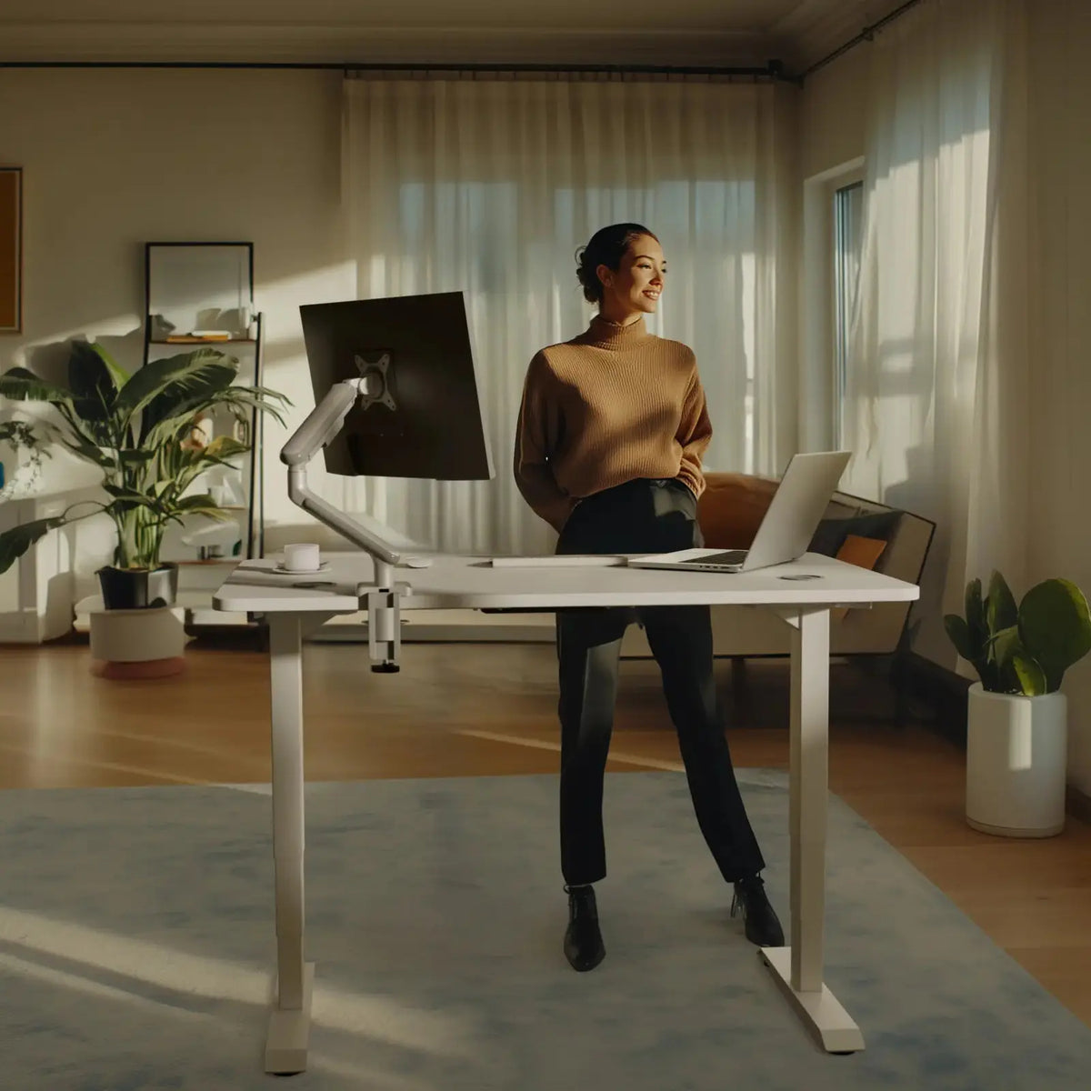 The desk with a white frame and a white top at standing height, a monitor arm clamped to the back edge (monitor, arm and laptop not included)